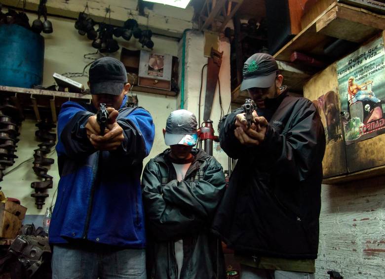 <b>Los tres cerditos</b>. Tres jóvenes sicarios apuntan al espectador con sus revólveres, recreando la historia de Los tres cerditos. Esta imagen, capturada en Barrio Triste, simboliza la cruda realidad que Ospina documenta: la violencia estructural y su impacto en los más vulnerables.